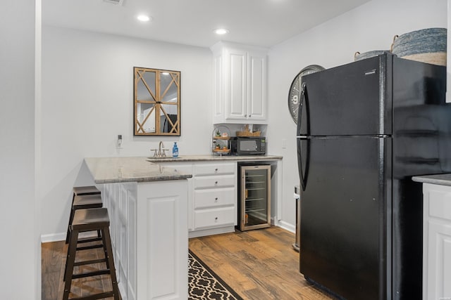 kitchen with black appliances, beverage cooler, dark wood-style floors, and white cabinets