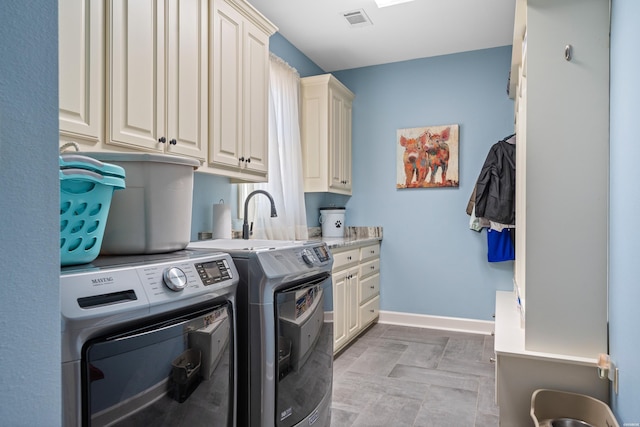 clothes washing area with visible vents, washing machine and clothes dryer, cabinet space, and baseboards