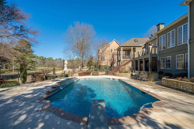 view of swimming pool featuring a fenced in pool, a patio, stairway, fence, and a diving board