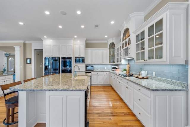 kitchen with fridge with ice dispenser, multiple ovens, a breakfast bar area, and tasteful backsplash