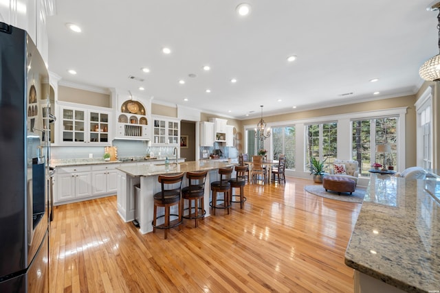 kitchen with tasteful backsplash, white cabinets, a kitchen breakfast bar, freestanding refrigerator, and crown molding