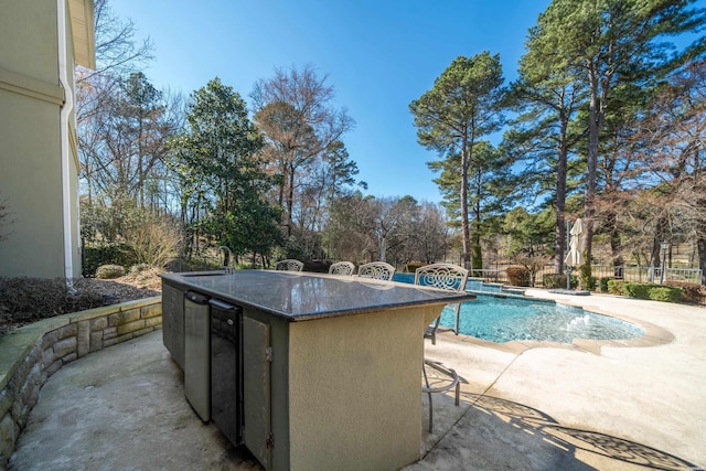 pool featuring outdoor dry bar, a patio area, and fence