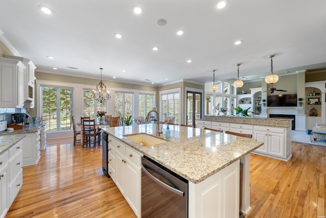 kitchen featuring a spacious island, a fireplace, a sink, ornamental molding, and dishwasher