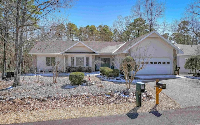 ranch-style house featuring aphalt driveway and an attached garage