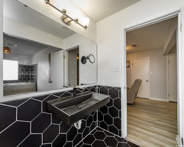 bathroom with visible vents, a sink, a textured ceiling, and wood finished floors