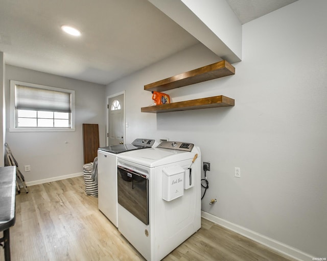 clothes washing area with washing machine and clothes dryer, laundry area, light wood-type flooring, and baseboards