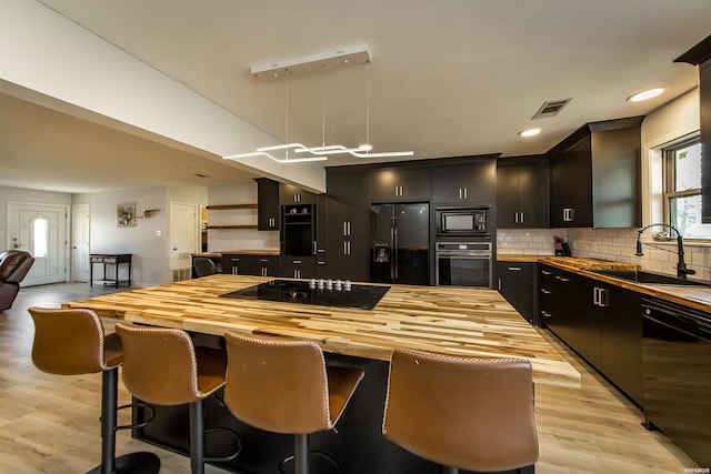 kitchen with visible vents, a sink, black appliances, backsplash, and butcher block counters