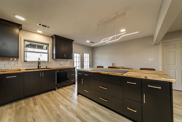 kitchen with light wood-style flooring, black appliances, dark cabinets, and butcher block counters