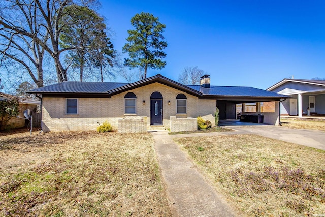 ranch-style home featuring an attached carport, driveway, a chimney, brick siding, and metal roof