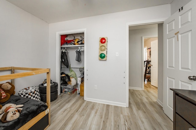 bedroom with a closet, baseboards, and light wood-style flooring