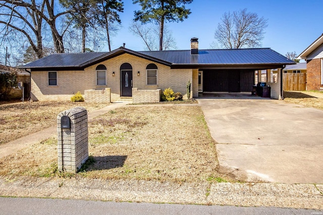 single story home featuring metal roof, driveway, brick siding, and a chimney