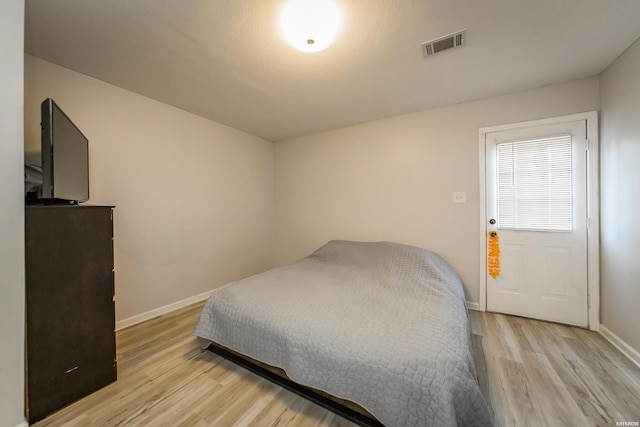 bedroom with visible vents, light wood-type flooring, and baseboards