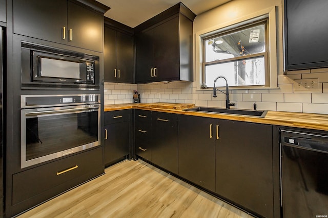 kitchen featuring a sink, black appliances, tasteful backsplash, and butcher block countertops