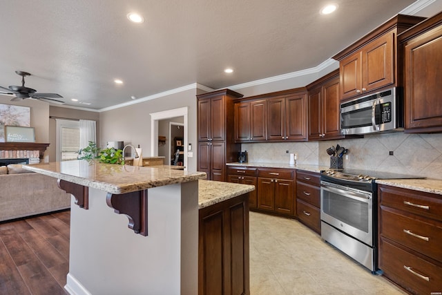 115 Gatehills Pl, Hot Springs, AR 71913 - kitchen with stainless steel appliances, open floor plan, a kitchen bar, a ceiling fan, and crown molding