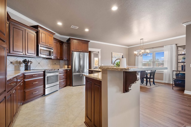 115 Gatehills Pl, Hot Springs, AR 71913 - kitchen with stainless steel appliances, crown molding, a chandelier, a breakfast bar area, and tasteful backsplash