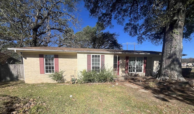 ranch-style home with brick siding, a front lawn, and fence