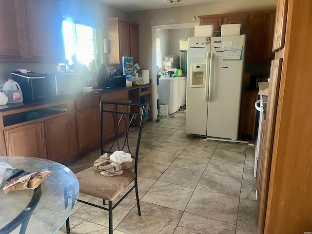 kitchen with white refrigerator with ice dispenser, washer / dryer, and brown cabinets