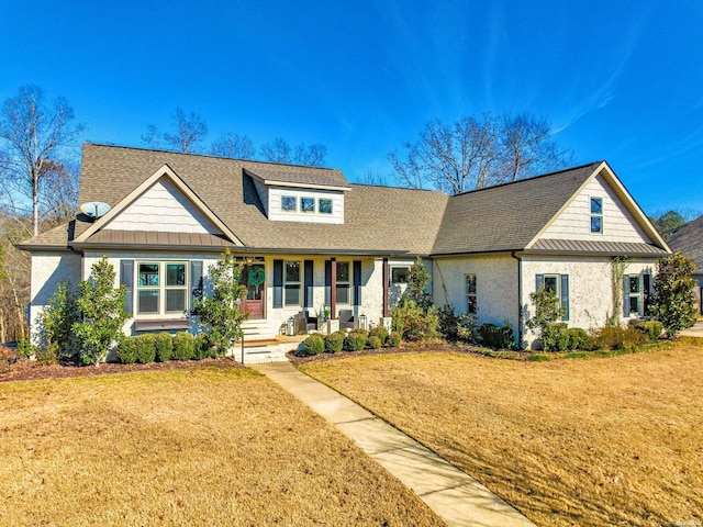 view of front of property with covered porch, roof with shingles, a front yard, and a standing seam roof