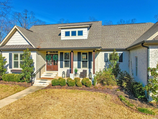 view of front of property featuring a front yard, covered porch, and roof with shingles