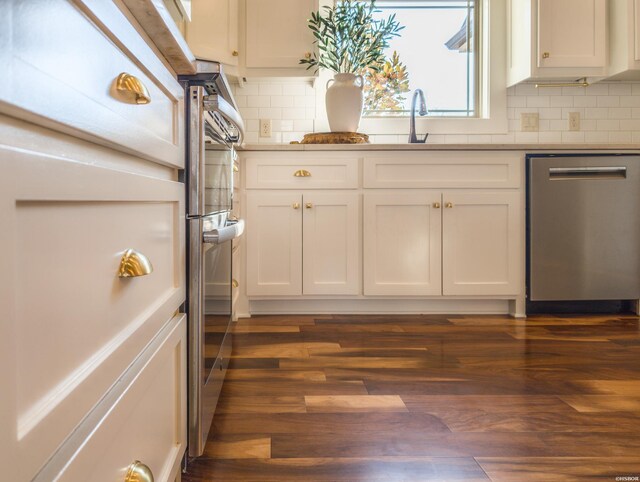 kitchen with a sink, white cabinetry, dark wood-style flooring, and stainless steel dishwasher