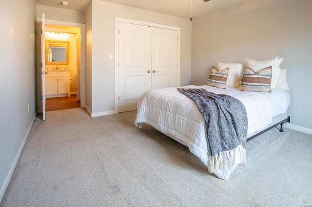 bedroom with baseboards, a closet, and light colored carpet