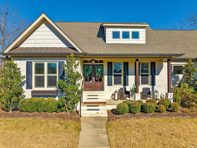 view of front of house featuring roof with shingles, a front lawn, a porch, and french doors