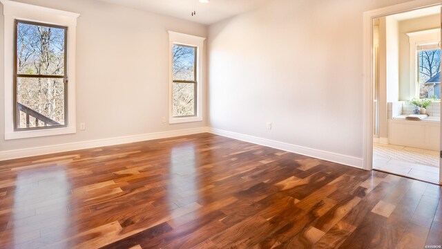 unfurnished room with dark wood finished floors and baseboards