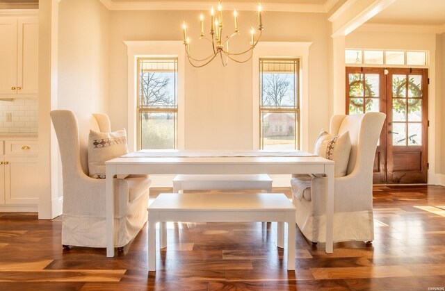 dining area featuring dark wood-style floors, ornamental molding, and a notable chandelier