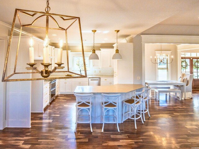 kitchen featuring dark wood-style flooring, white cabinets, hanging light fixtures, dishwasher, and tasteful backsplash