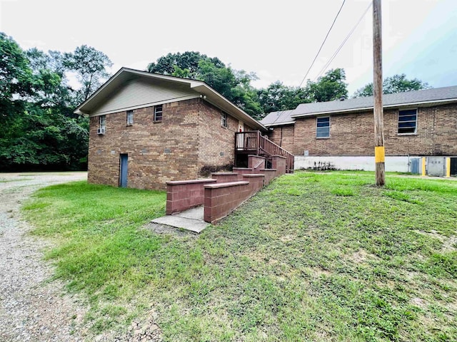 view of side of home with driveway, brick siding, stairway, and a lawn