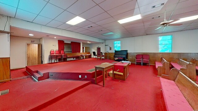 rec room with a wainscoted wall, a drop ceiling, and visible vents