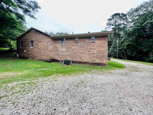 view of home's exterior with a yard, central AC, and brick siding