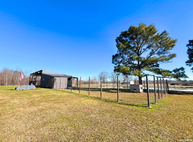 view of yard featuring fence, a pole building, and an outdoor structure