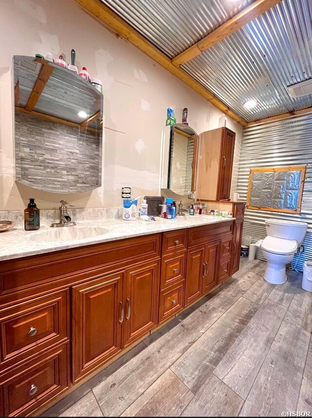 bathroom featuring double vanity, wood finished floors, a sink, and toilet