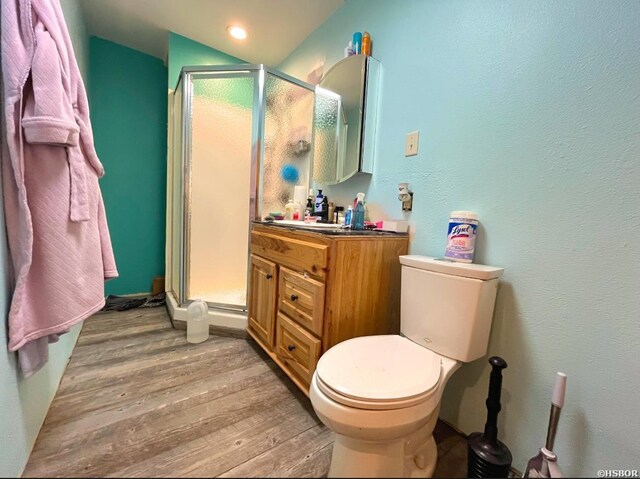 bathroom featuring a stall shower, vanity, toilet, and wood finished floors