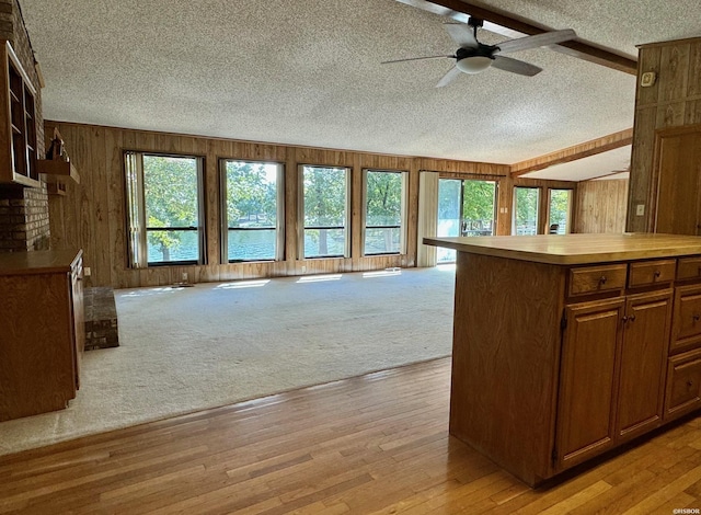 kitchen with open floor plan, light countertops, a center island, and wooden walls