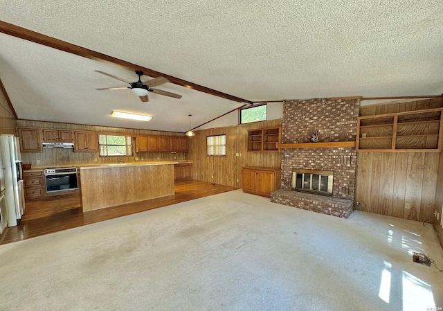 unfurnished living room with vaulted ceiling with beams, wood walls, a fireplace, and a textured ceiling