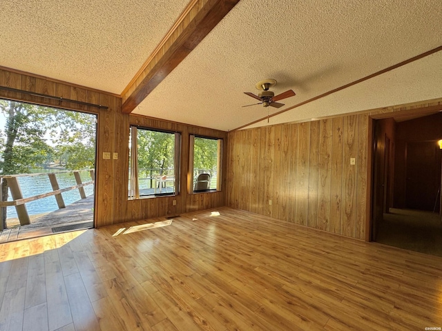 spare room with vaulted ceiling, a textured ceiling, wood finished floors, and wooden walls