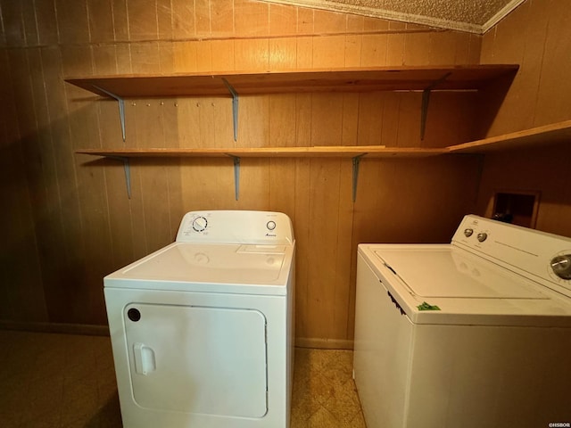 clothes washing area featuring wood walls, laundry area, and washer and dryer