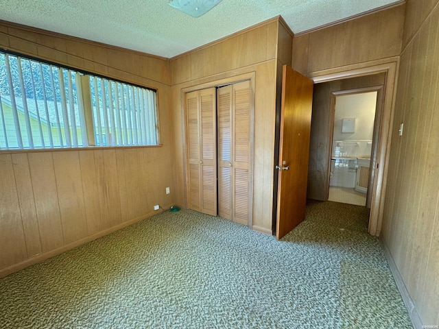 unfurnished bedroom with carpet, a closet, wooden walls, and a textured ceiling