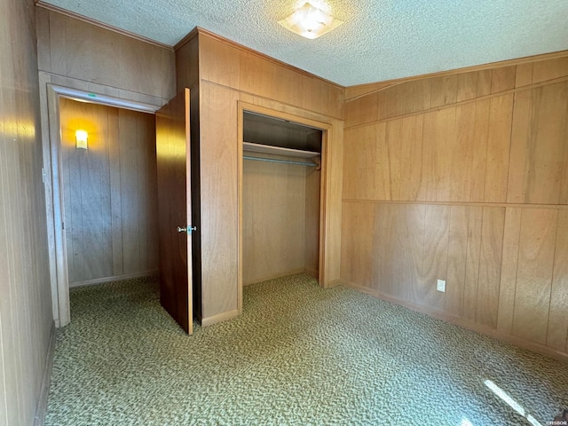 unfurnished bedroom with a closet, light colored carpet, wooden walls, and a textured ceiling