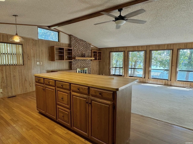 kitchen with lofted ceiling with beams, wood counters, a center island, hanging light fixtures, and open shelves