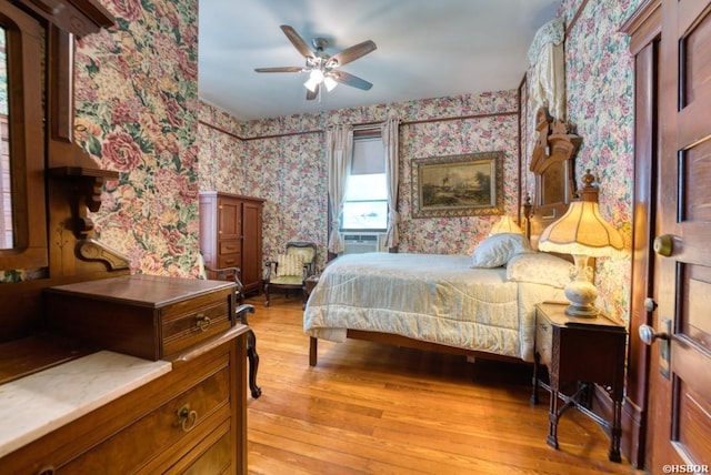 bedroom featuring wallpapered walls, a ceiling fan, cooling unit, and light wood-style floors