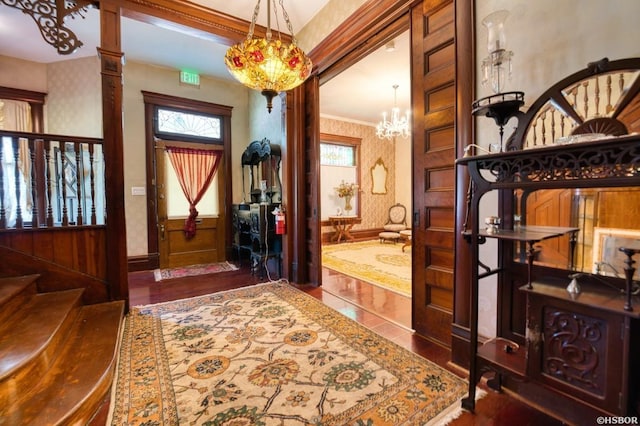 foyer entrance featuring ornate columns, ornamental molding, stairway, and wallpapered walls