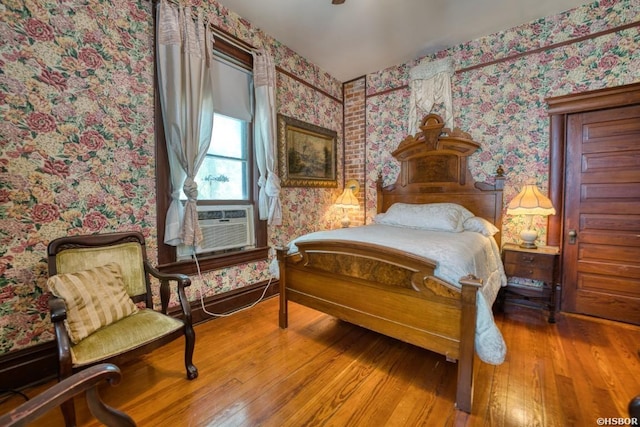 bedroom featuring wallpapered walls, cooling unit, and wood finished floors