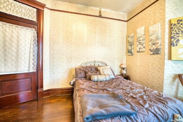 bedroom with wallpapered walls and dark wood-type flooring