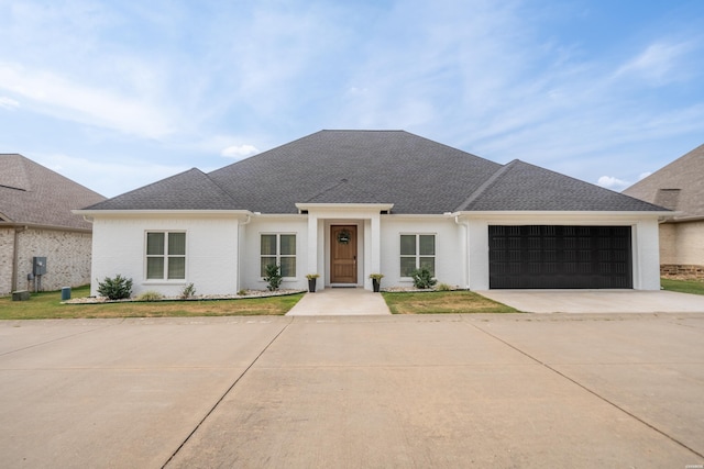 view of front of house with a garage, a front lawn, concrete driveway, and roof with shingles