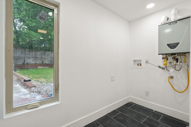 207 Hagen St, Hot Springs, AR 71913 - laundry room featuring a healthy amount of sunlight, tankless water heater, laundry area, dark tile patterned floors, and baseboards