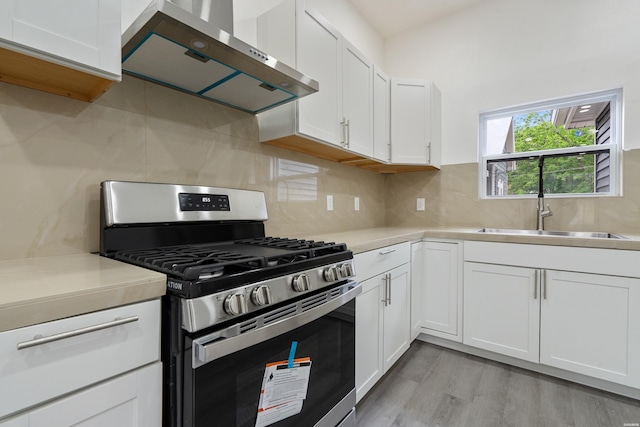 207 Hagen St, Hot Springs, AR 71913 - kitchen featuring wall chimney range hood, white cabinets, a sink, light countertops, and stainless steel gas range oven