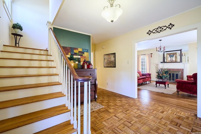 stairs with ornamental molding, a notable chandelier, a fireplace, and baseboards